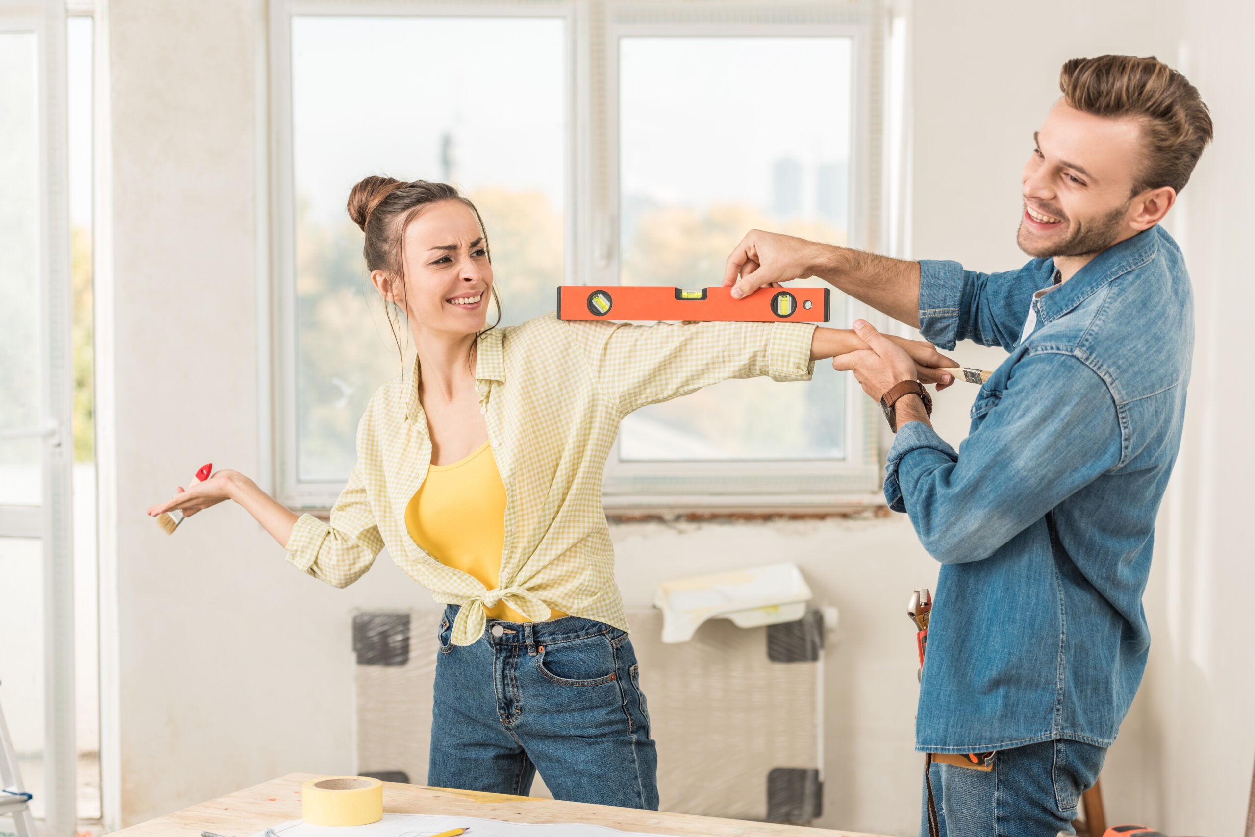 happy young couple having fun with tools during DIY project scaled